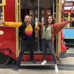 Spring Break New Orleans 2023 represented by two college students posing on the steps of a streetcar