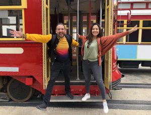 Spring Break New Orleans 2023 represented by two college students posing on the steps of a streetcar